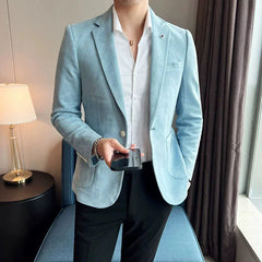 A man wears a light blue slim-fit deerskin velvet blazer with a white shirt and black trousers.