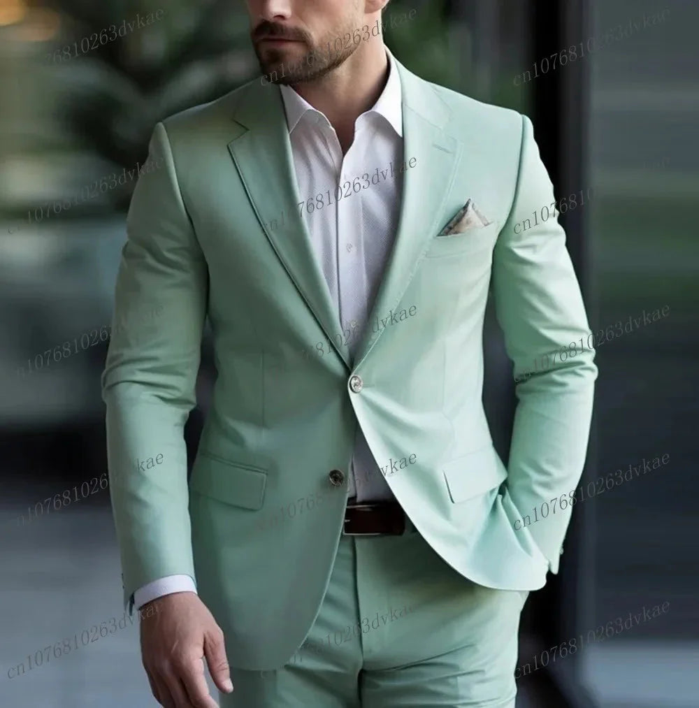 A man wears a light green two-piece formal suit with a white dress shirt.