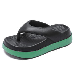 A pair of black platform flip-flops with a thick green sole and a textured footbed.