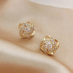 Gold-tone stud earrings featuring a central zircon stone surrounded by a hollow geometric knot.