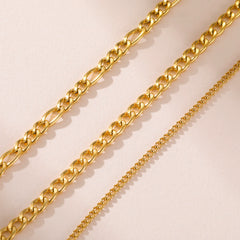 Three gold-toned stainless steel chains of varying thicknesses are displayed against a light background.