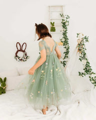 A girl wears a sage green floor-length tulle dress with a floral embroidered bodice and lace back.