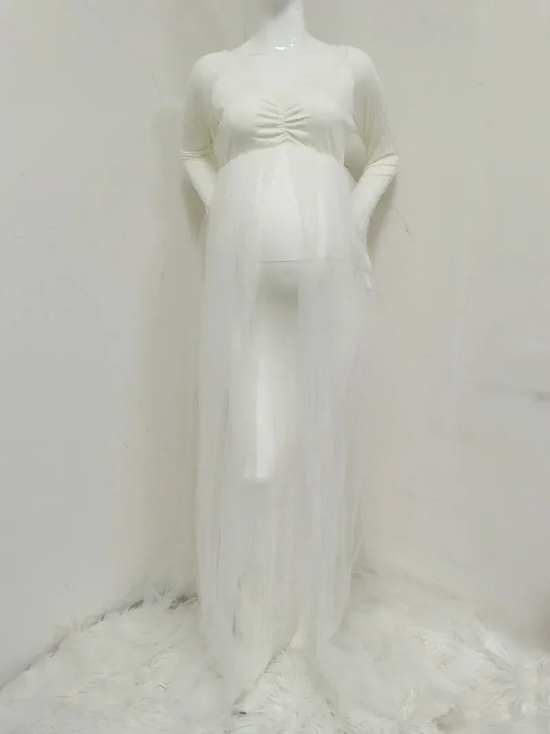 A white long-sleeved maternity dress with a ruched bodice and a sheer tulle overlay.