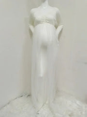 A white long-sleeved maternity dress with a ruched bodice and a sheer tulle overlay.