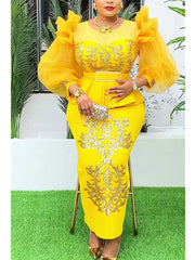 A woman wears a bright yellow long-sleeved evening gown with gold sequin embroidery and a belt.
