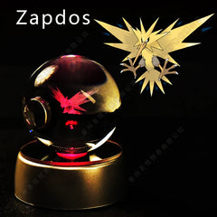 A glass crystal ball featuring a 3D laser-etched Zapdos, resting on an illuminated base.