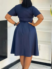 A woman wears a navy blue short-sleeved knee-length A-line swing dress from the back.