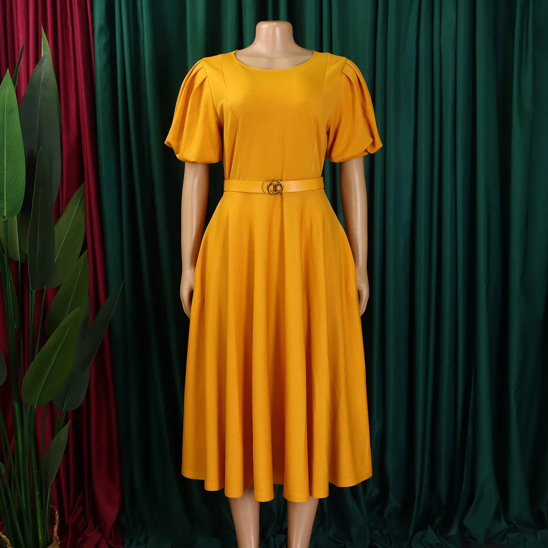 A mustard yellow midi dress with short puff sleeves, a round neckline, and a matching waist belt.