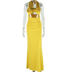 A yellow ankle-length halter dress featuring two fabric roses on the bodice and a cutout waist.