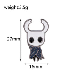 A Hollow Knight enamel pin featuring the white-masked insectoid character with a blue cloak.