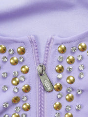 A close-up of a lavender dress featuring a front zipper closure and gold stud and crystal embellishments.