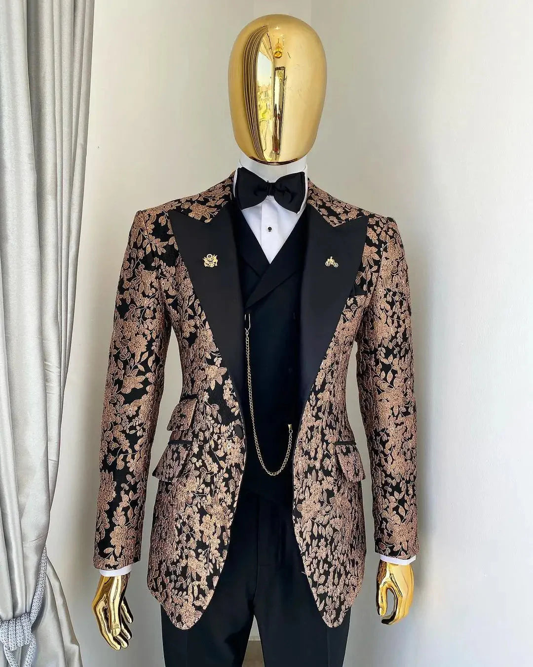 A three-piece men's suit featuring a black and gold floral jacquard blazer with black lapels.