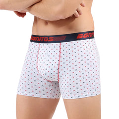 A man wears white cotton boxer shorts featuring a small red and black cross pattern.