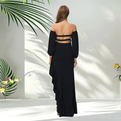 A woman wears a black off-shoulder maternity dress with long sleeves and a ruffled hem.