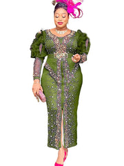 A woman wears a long-sleeved olive green maxi dress decorated with rhinestones and a belt.