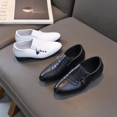 A pair of black and a pair of white boys' formal loafers with decorative side buckles.