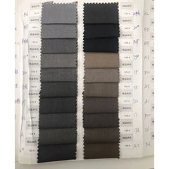 A fabric swatch book displays a variety of gray and brown textile samples for men's suits.
