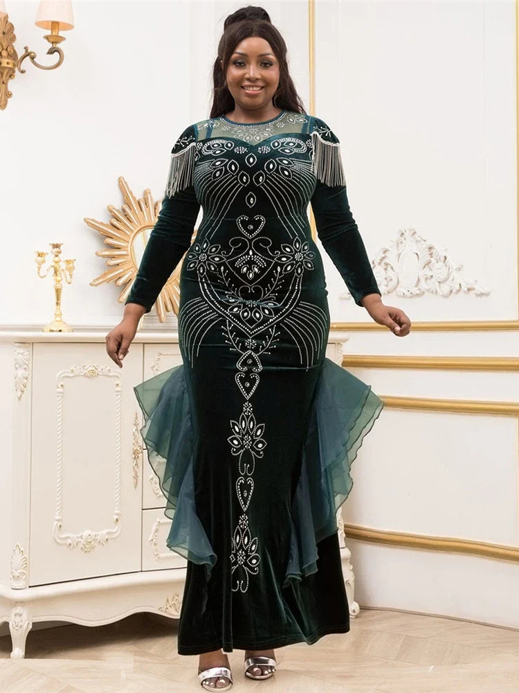 A woman wears a long-sleeved, floor-length dark green velvet mermaid gown with crystal embellishments.