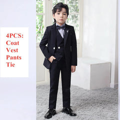 A young boy wears a formal black four-piece suit consisting of a blazer, vest, trousers, and tie.