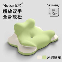 A light green and white memory foam pillow with an irregular shape designed for comfortable prone positioning.