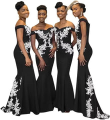Four women wear matching black off-the-shoulder mermaid dresses with white floral lace appliques.
