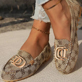 Beige fabric loafers featuring a repeating brown pattern and a gold-tone metal buckle detail.