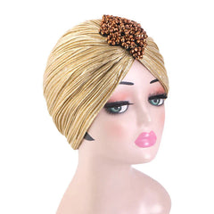 A gold pleated turban headscarf for women featuring a decorative cluster of brown beads.