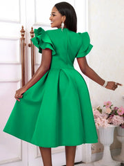 A woman wears a knee-length green A-line dress with ruffled sleeves and a pleated skirt.