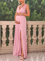 A pregnant woman wears a sleeveless, ankle-length pink maternity dress with a V-neck and side slit.