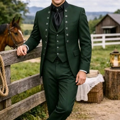 A man wears a dark green three-piece suit with a mandarin collar jacket and black shirt.