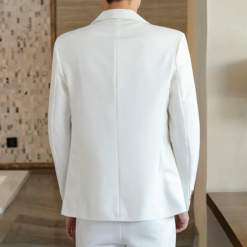 A man wearing a slim-fit white two-piece suit viewed from the back.