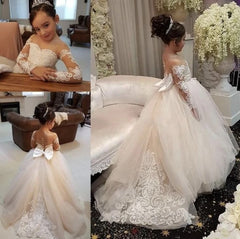 A flower girl dress with sheer lace sleeves, a big back bow, and a full tulle skirt.