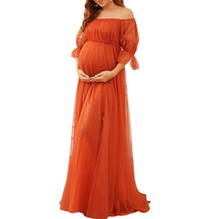 A pregnant woman wears an off-shoulder, short-sleeve, burnt orange tulle maternity gown.