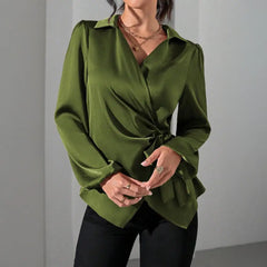 A woman wears an olive green satin wrap blouse with long sleeves and a side tie waist.