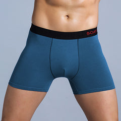 A man wearing blue cotton boxer shorts with a black waistband featuring red lettering.