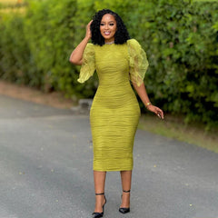 A woman wears a lime green, mid-calf bodycon dress with ruffled butterfly sleeves and a textured finish.