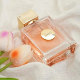 A rectangular glass bottle of Armaf Club De Nuit perfume with a gold cap and a hanging logo charm.