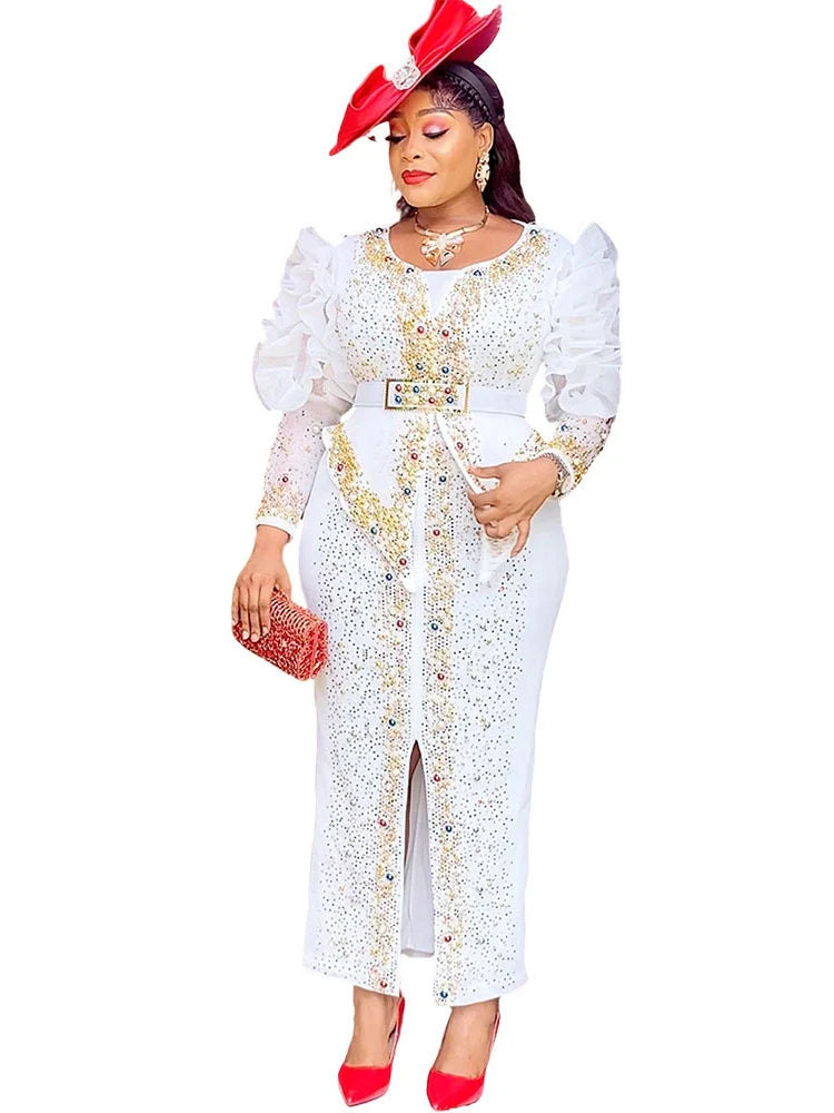 A woman wears a white, ankle-length puff sleeve gown decorated with gold and colorful diamonds.