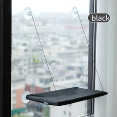 A black cat hammock hangs from a window using four suction cups and thin support cables.