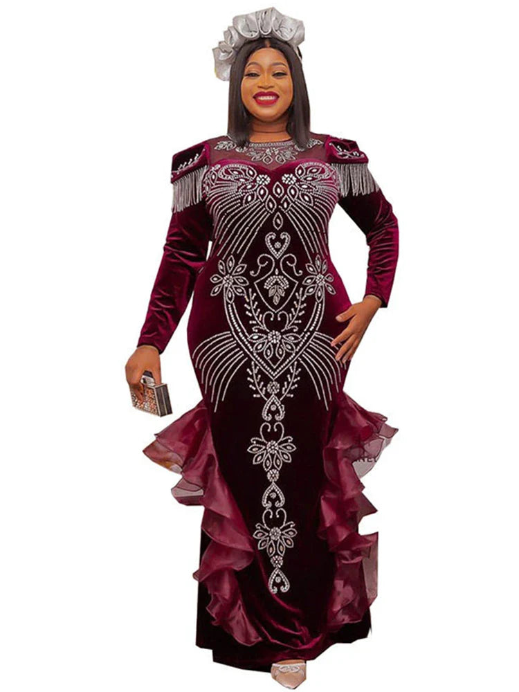 A woman wears a long-sleeved, floor-length burgundy velvet mermaid gown with crystal embellishments.