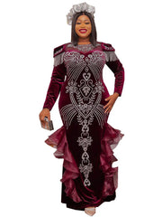A woman wears a long-sleeved, floor-length burgundy velvet mermaid gown with crystal embellishments.