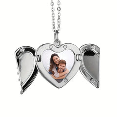 A silver heart-shaped locket necklace with open angel wings displaying a photo of a couple.