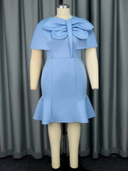 A light blue mini dress with a round neck, short cape sleeves, a large bow, and a ruffled hem.