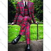 A man wears a three-piece red plaid suit with a peak lapel jacket, vest, and matching trousers.