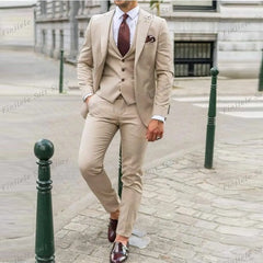 A man wears a beige three-piece suit with a white shirt and a dark brown tie.