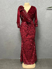 A floor-length burgundy mermaid gown with a V-neck, sequined skirt, and floral shoulder detail.