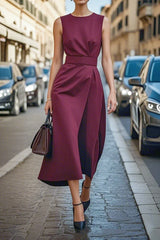 A sleeveless, ankle-length burgundy dress with an asymmetrical wrap skirt and a fitted waist.