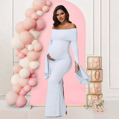 A pregnant woman wears a white off-shoulder long-sleeve mermaid dress for a photoshoot.