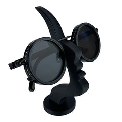 A minimalist black 3D-printed stand shaped like a human profile holding round sunglasses.
