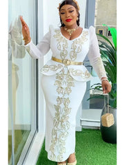 A woman wears a white long-sleeved dress with gold embroidery, a peplum waist, and a gold belt.